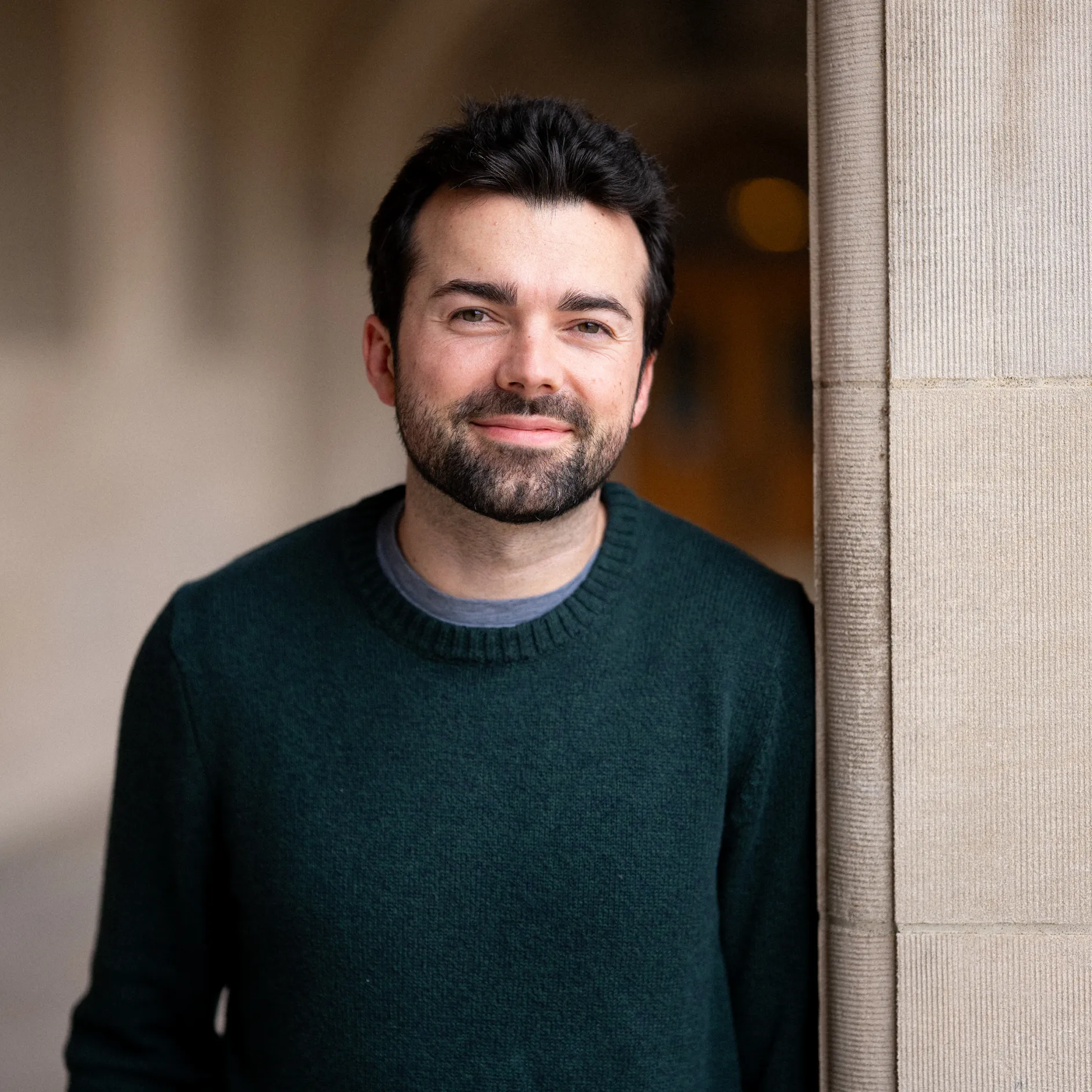 KJ Schaeffner smiles for a photo while leaning against a pillar outside Ridgley Hall