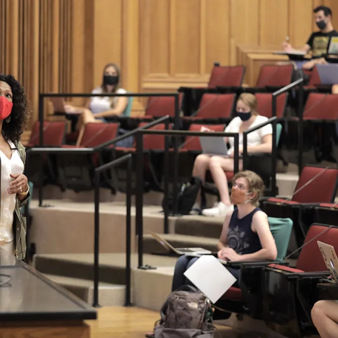 teacher in mask giving lecture to students